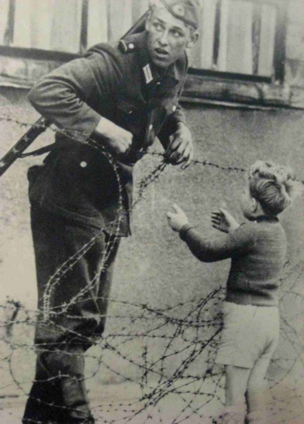 16.) An East German soldier helps a little boy escape to his family in the west.