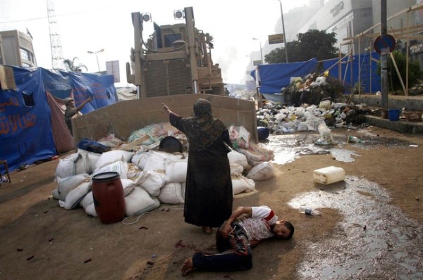 14.) A wounded protestor is protected by a woman from a military bulldozer in Egypt in 2013.