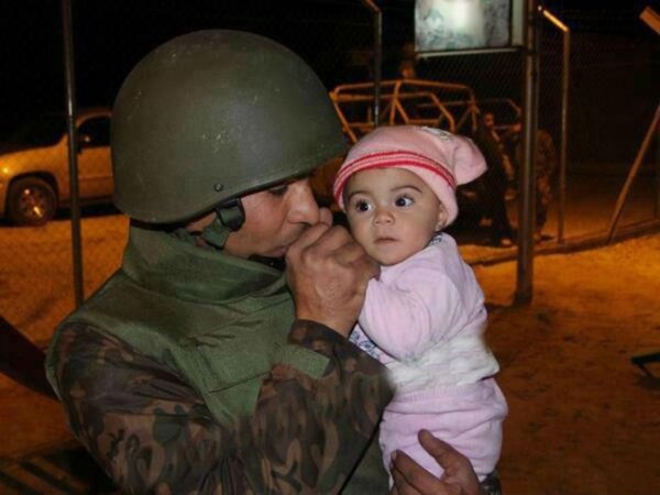 24.) A Jordanian soldier keeps a Syrian baby warm after she was evacuated because of the civil war there.
