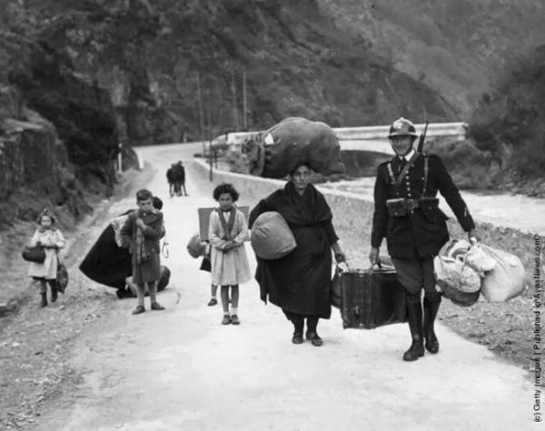 20.) A French soldier helps a family flee danger during the Spanish Civil War in 1938.