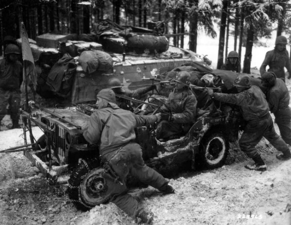 12.) American soldiers push a car carrying two severely wounded German soldiers, 1945.