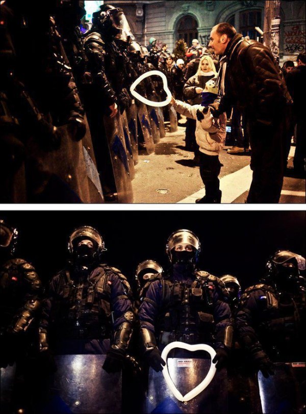 25.) During protests in Romania in 2012, a young boy gives riot police a heart shaped balloon.