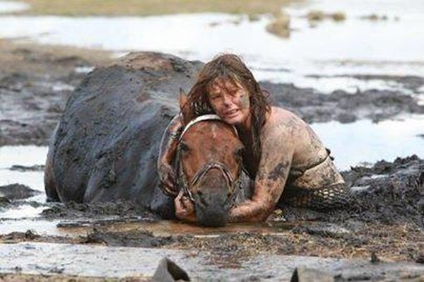 11. A woman helping a horse who got stuck in mud.