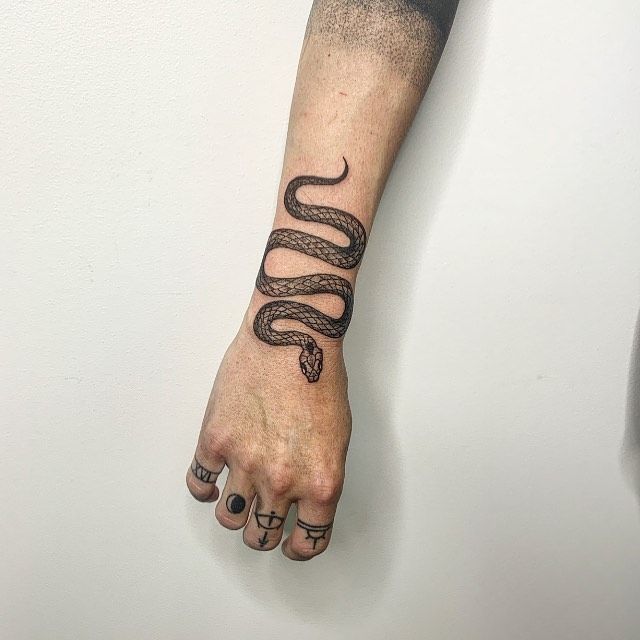 Snake and moon tattoo placed on the wrist