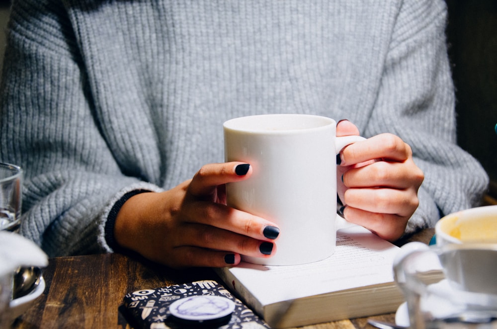 woman holding white ceramic mug