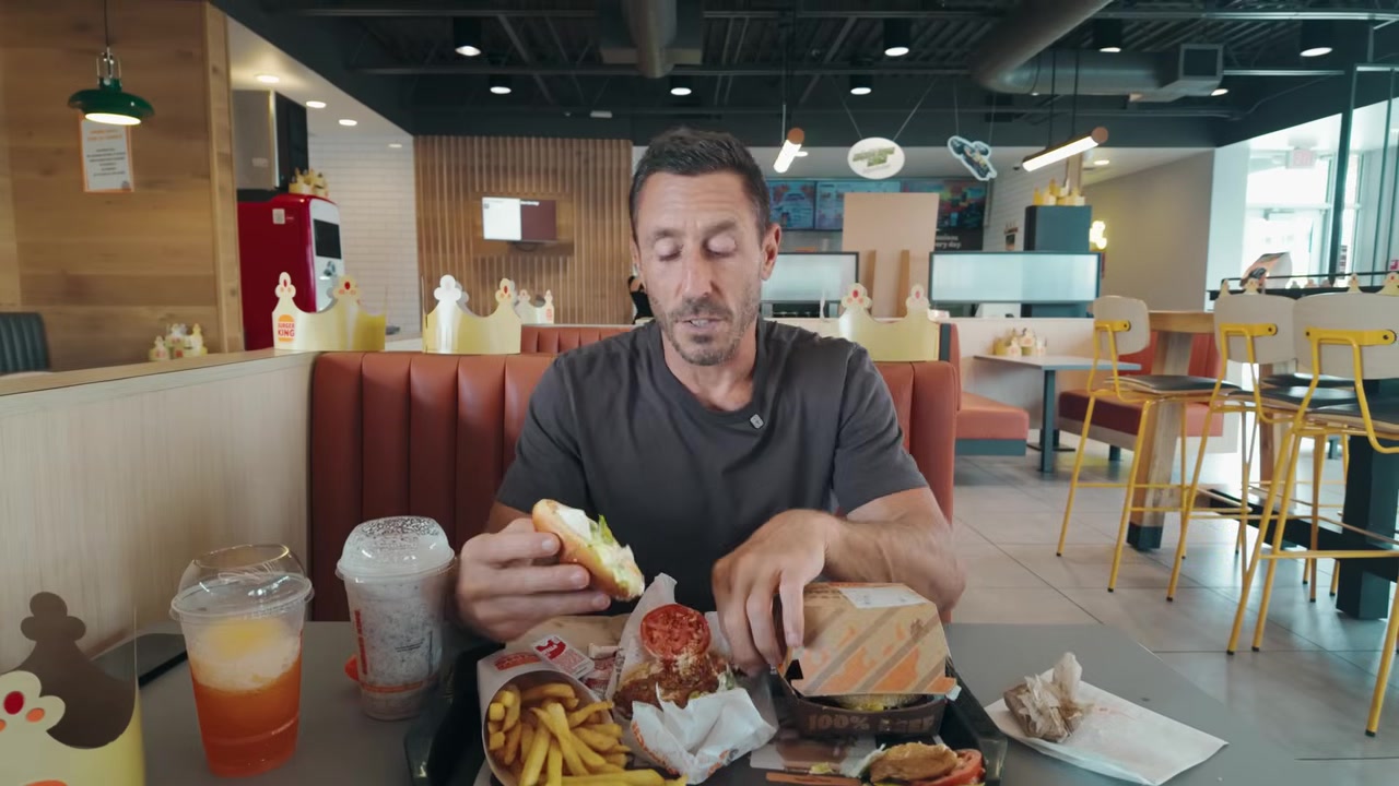 The spicy chicken sandwich is held up and examined, showing multiple layers of breading