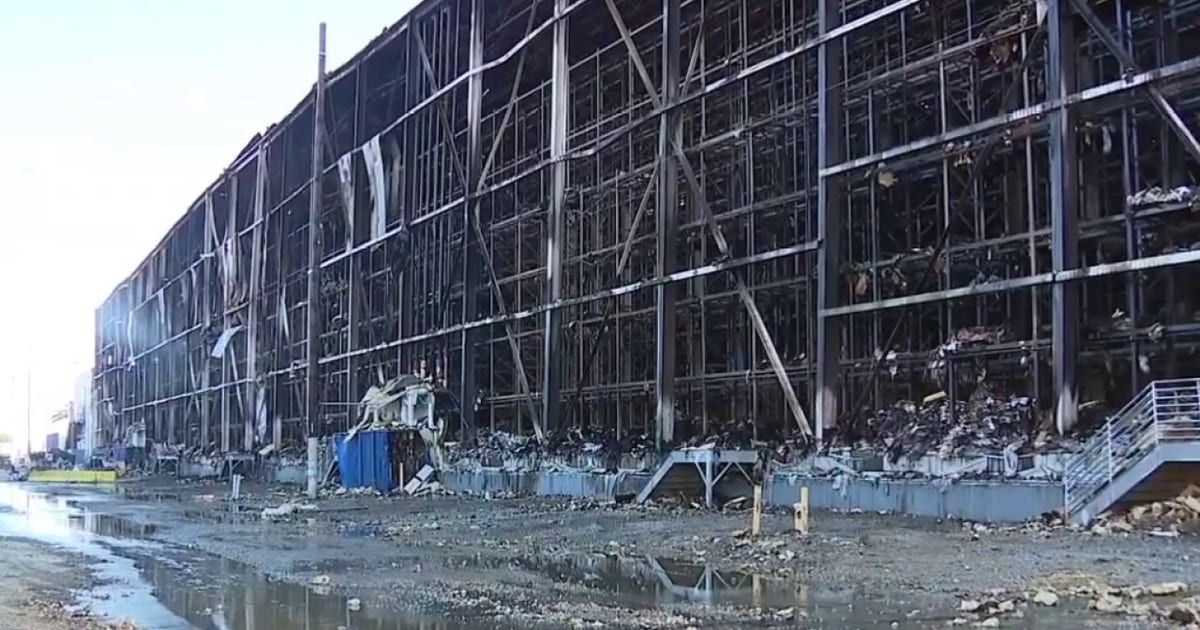 The charred remains of the Lineage warehouse surrounded by cleanup debris