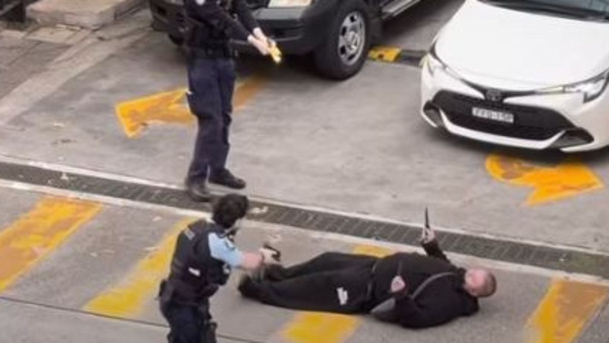 The arrested suspect being restrained by multiple police officers