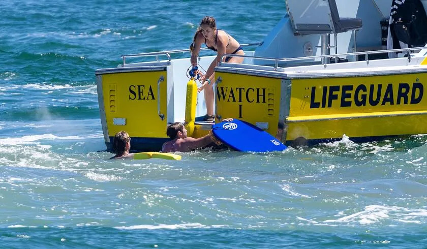Beachgoers in powerful ocean surf during the heat wave weekend