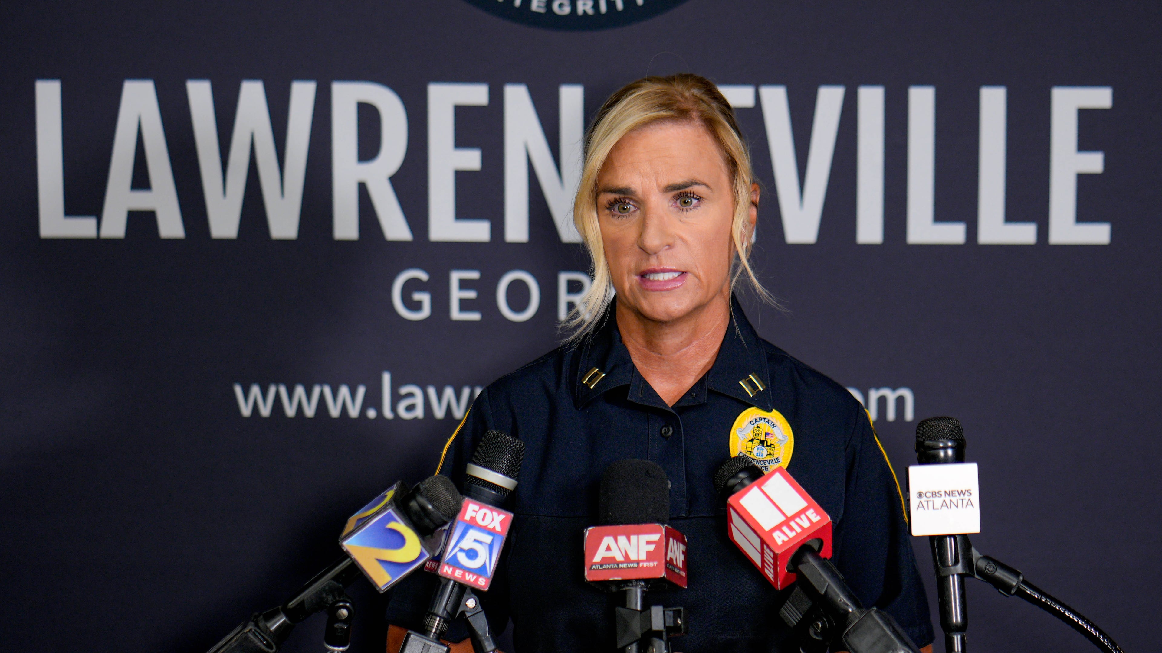 Captain Dena Pauly speaking at a podium during the announcement to media
