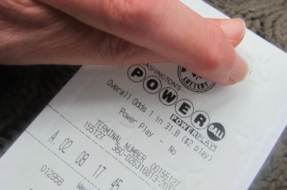 Lottery retail workers behind a counter with Powerball signage