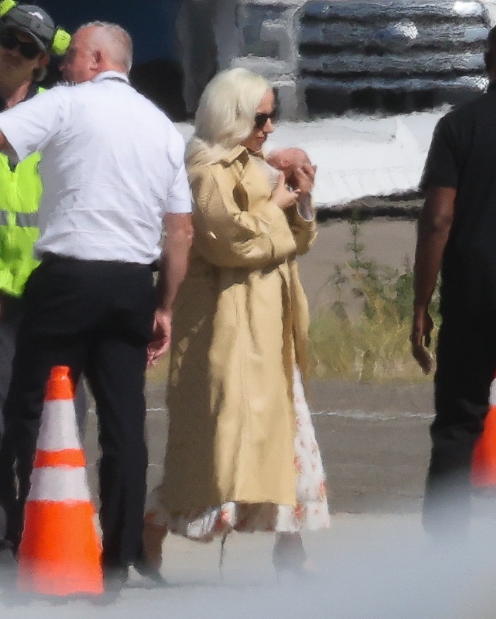 Glam Lady Gaga cradles her baby as she touches down in LA with fiancé Michael Polansky